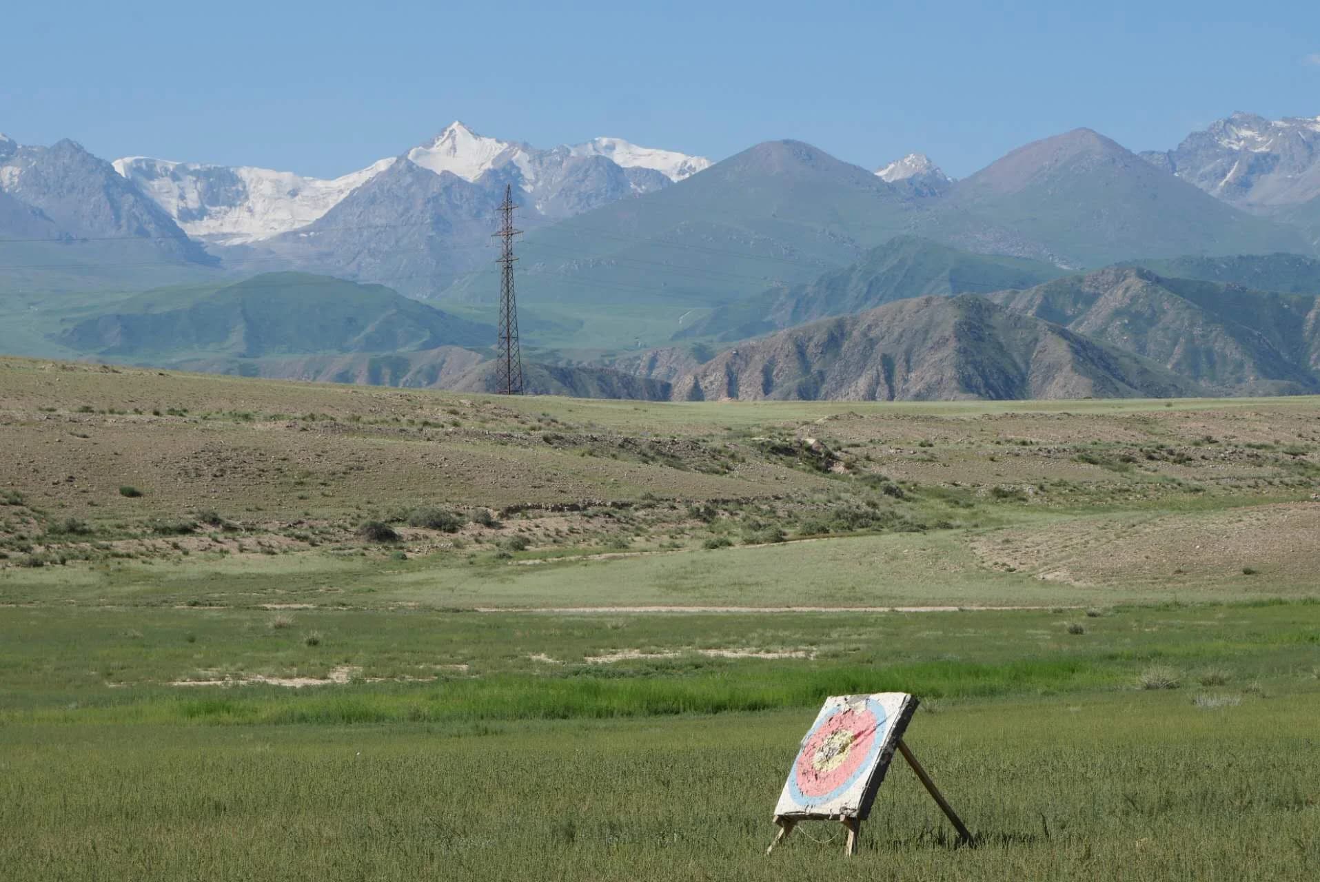 Open grassland with a target board and snow-capped mountains in the distance